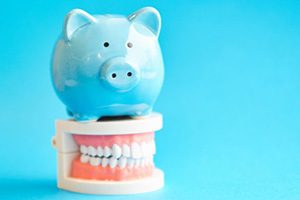 Piggy bank standing on top of model teeth