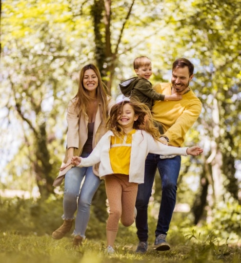 Family of four smiling while walking through a forest