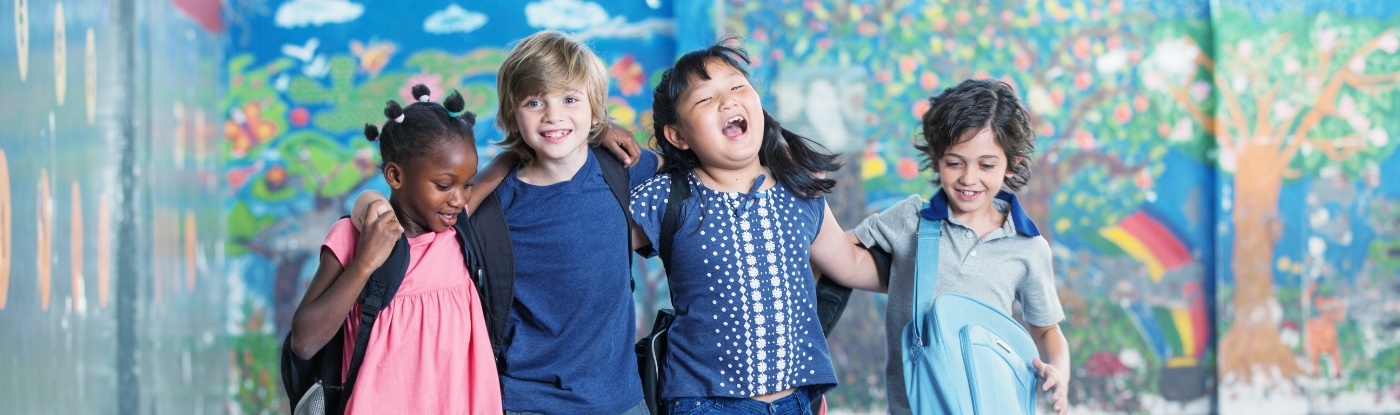 Four kids with backpacks standing in front of mural