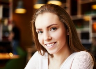 Young brunette woman smiling after receiving dental services in Allen