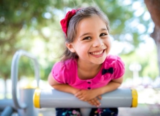 Young girl in pink blouse smiling on outdoor playground