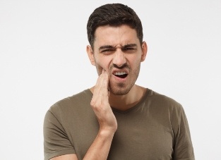 Man wincing in pain and holding the side of his jaw