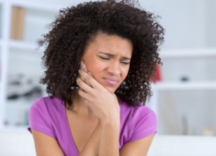 Woman wincing in pain and holding the side of her face