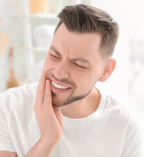 Man wincing and holding his jaw in pain