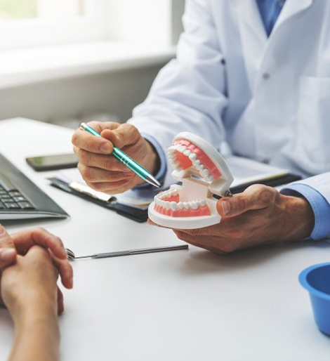 a dentist holding a model of dentures