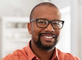 Smiling man in glasses and orange collared shirt