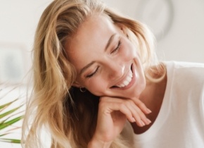 Blonde woman smiling and resting her hand on her chin