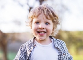 Blond child smiling excitedly outdoors