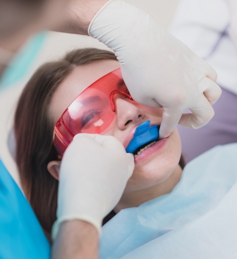 Young woman in dental chair having fluoride applied to her teeth