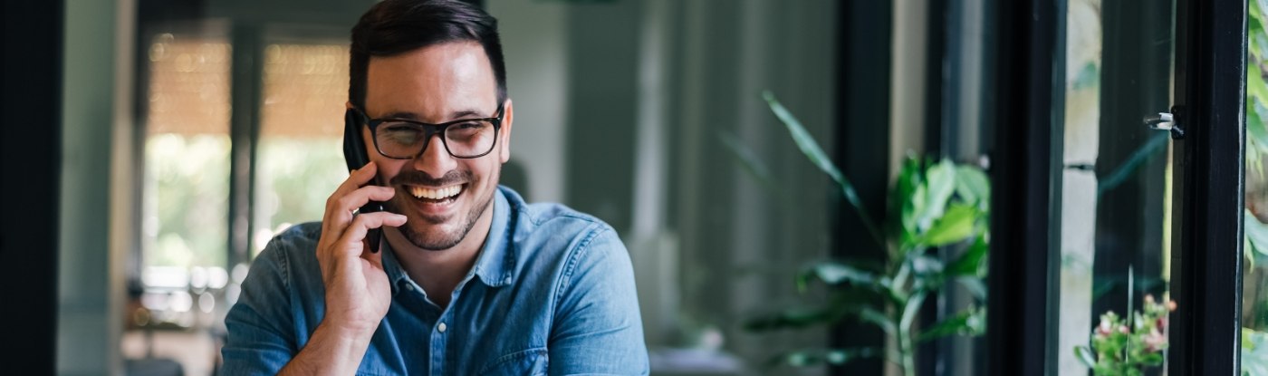 Smiling man in denim shirt talking on the phone