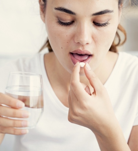 Woman taking a pill with a glass of water