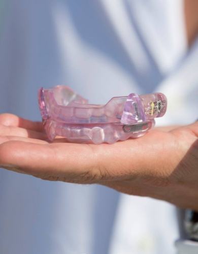 Hand holding a light purple occlusal splint tray